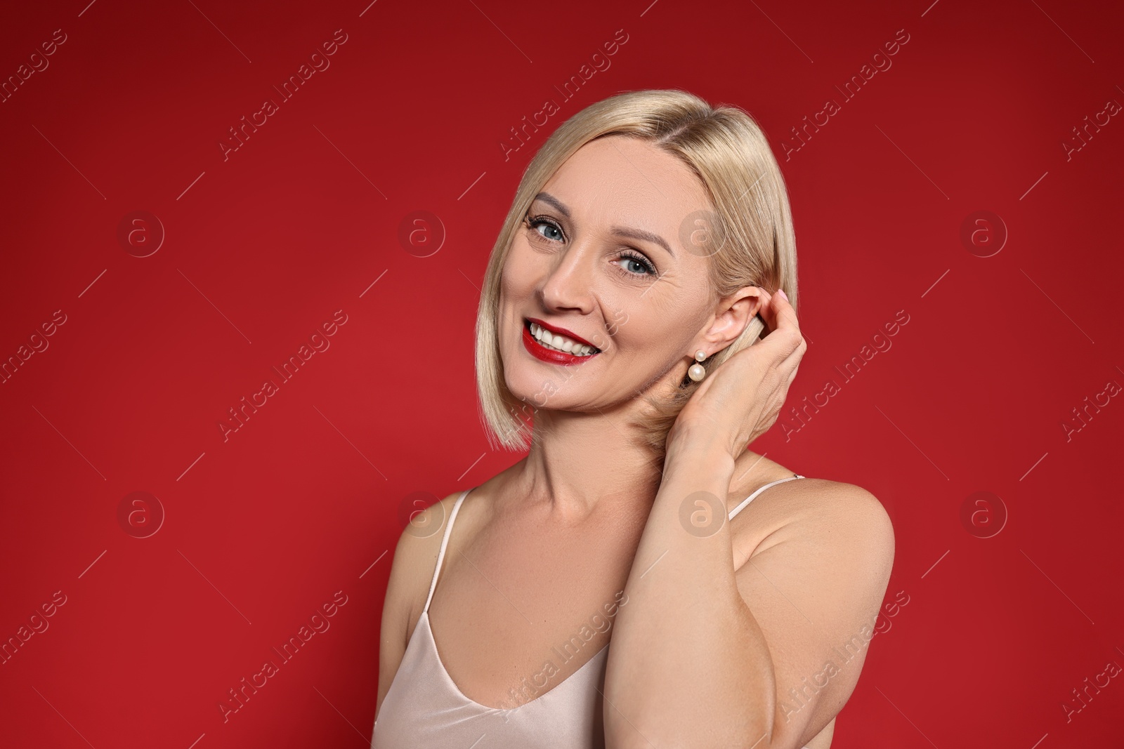 Photo of Smiling woman with perfect makeup on red background. Space for text