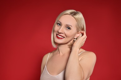 Photo of Smiling woman with perfect makeup on red background. Space for text