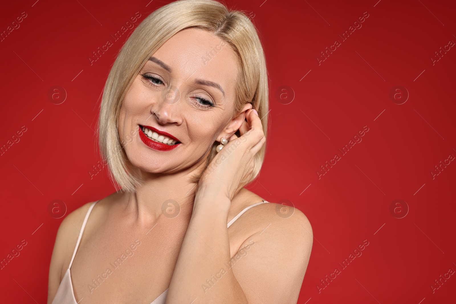 Photo of Smiling woman with perfect makeup on red background. Space for text