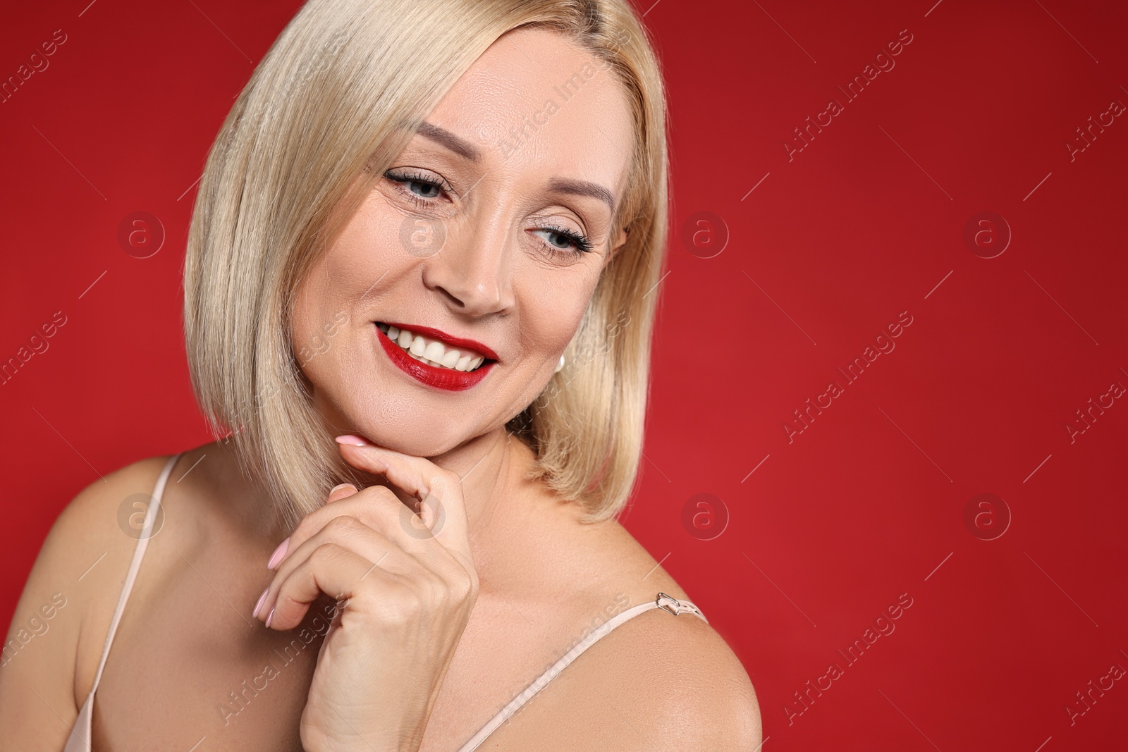 Photo of Smiling woman with perfect makeup on red background. Space for text