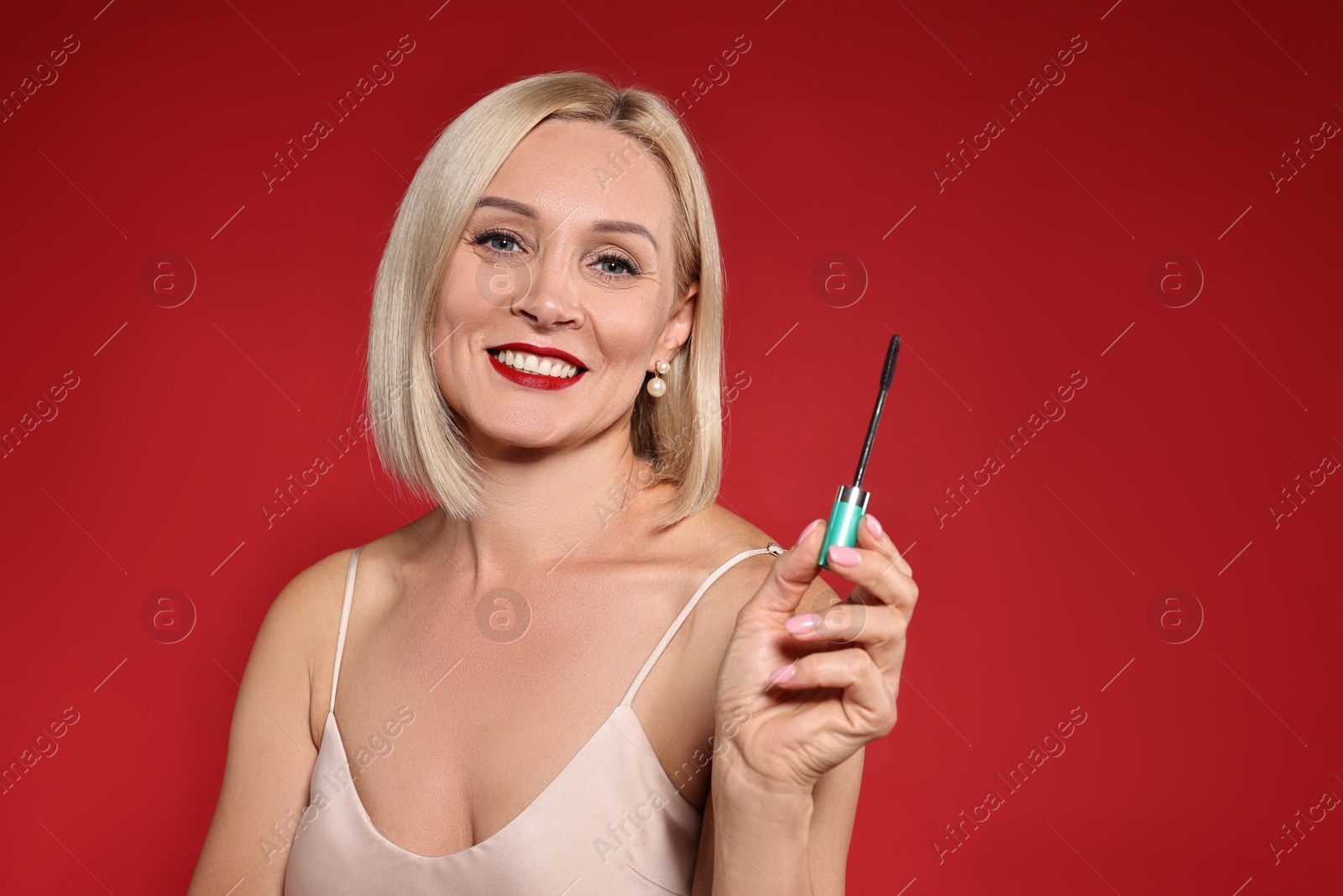 Photo of Smiling woman with makeup brush on red background