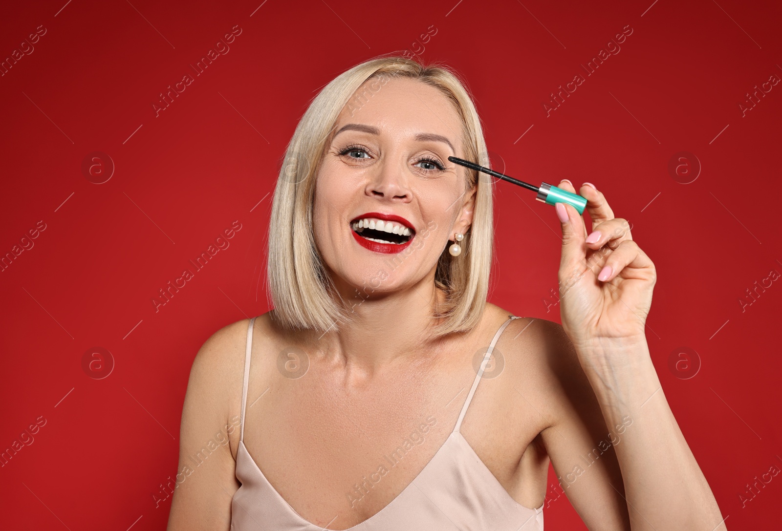 Photo of Happy woman with makeup brush on red background