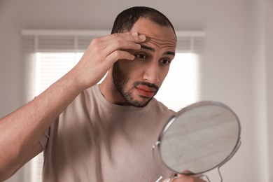 Photo of Worried man looking at mirror in room