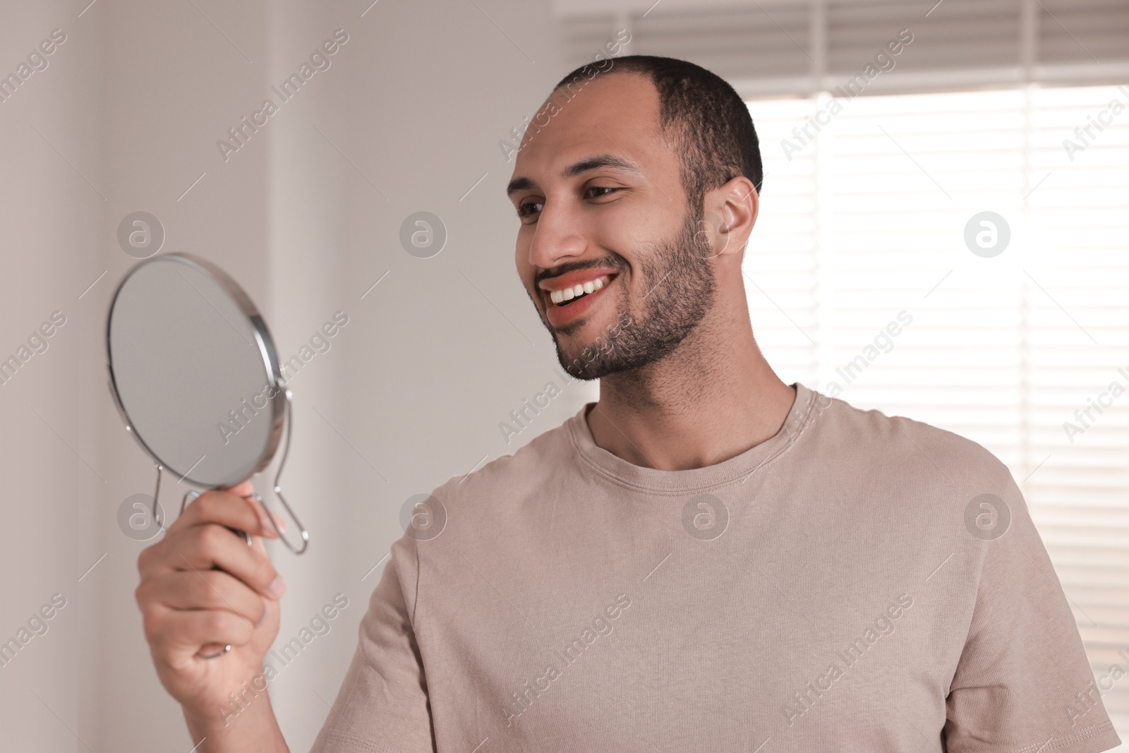 Photo of Smiling man looking at mirror in room