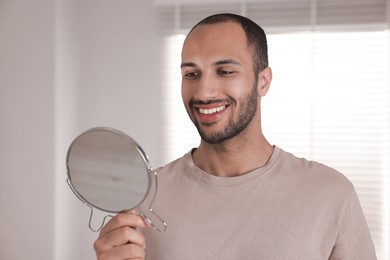 Photo of Smiling man looking at mirror in room