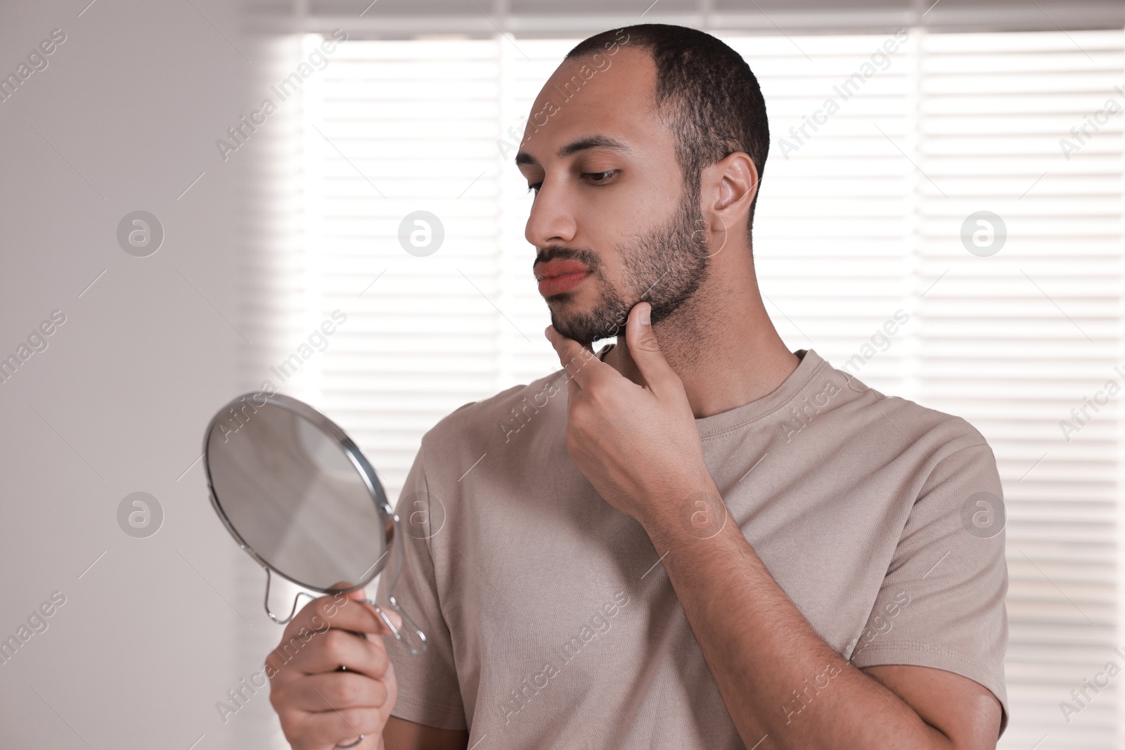 Photo of Handsome man looking at mirror in room