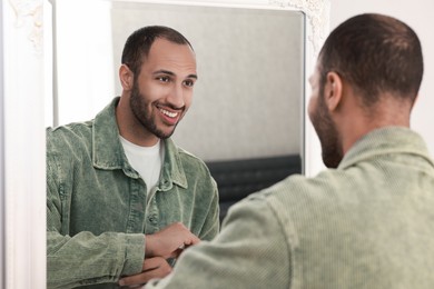 Smiling man dressing near mirror at home