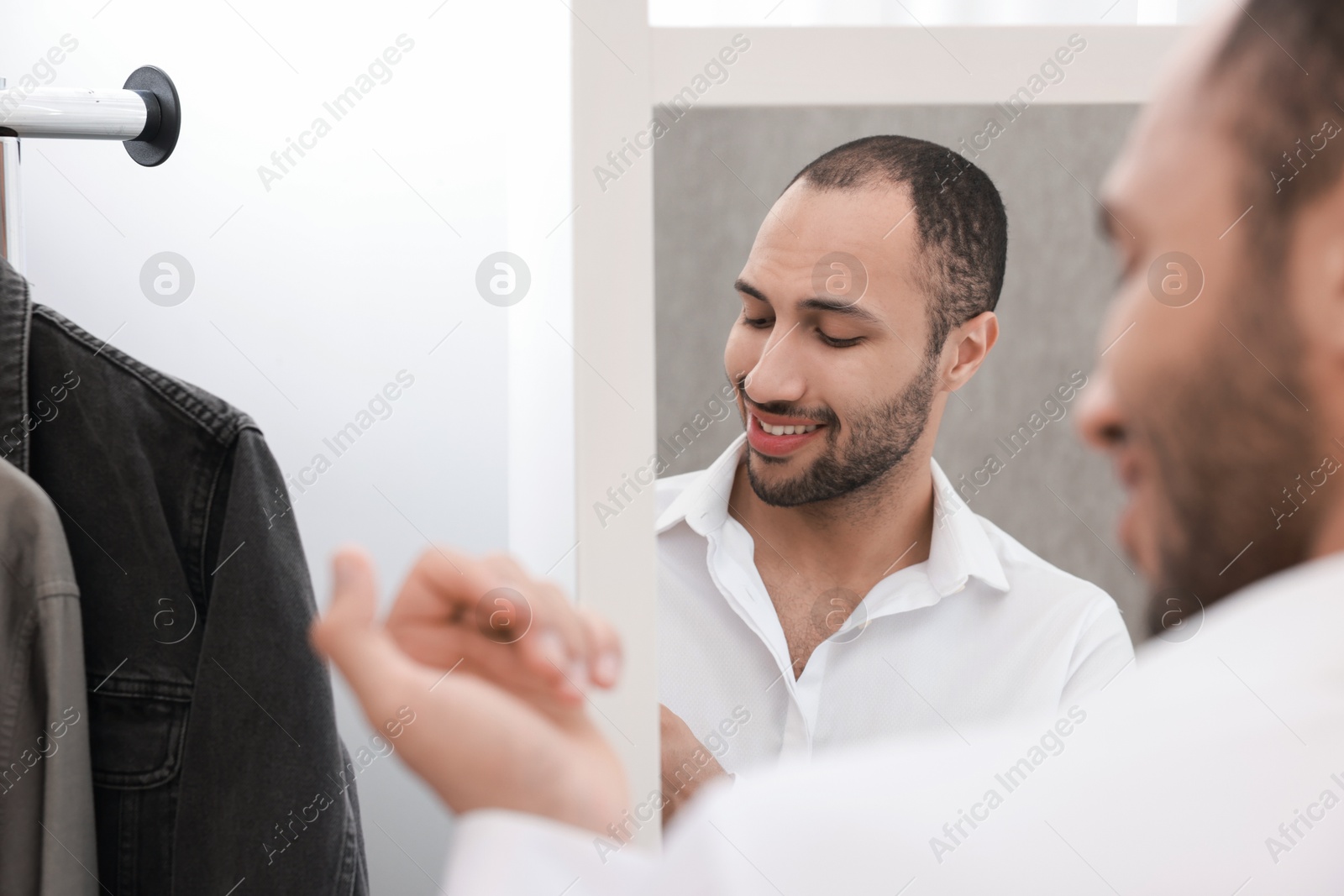 Photo of Smiling man dressing near mirror at home