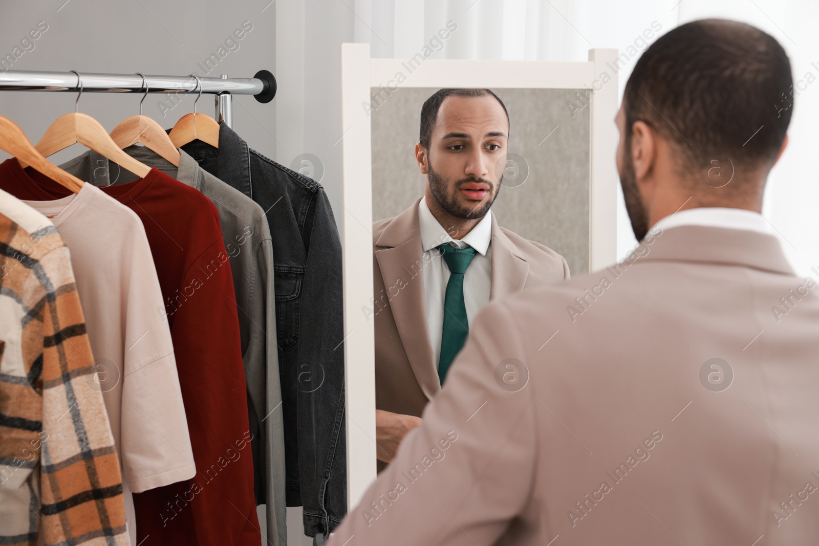 Photo of Handsome man looking at mirror at home, back view