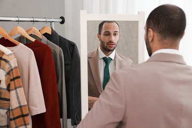 Photo of Handsome man looking at mirror at home, back view