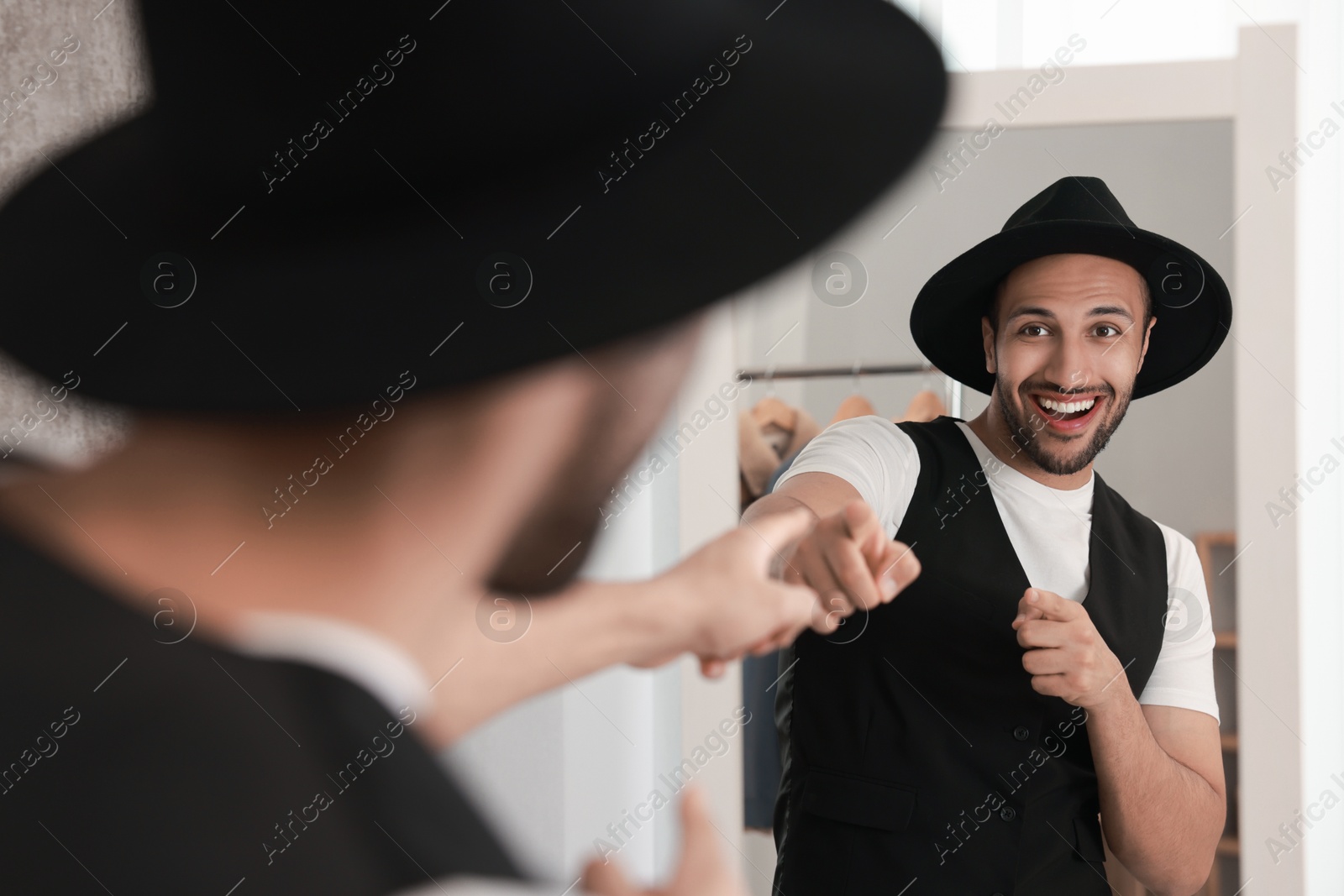 Photo of Smiling man looking at mirror at home