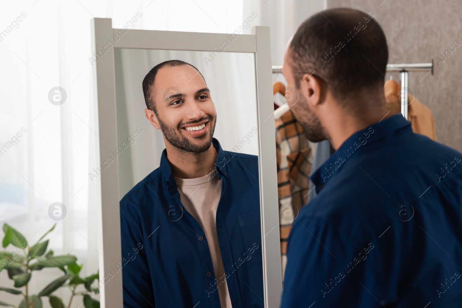 Photo of Smiling man looking at mirror at home