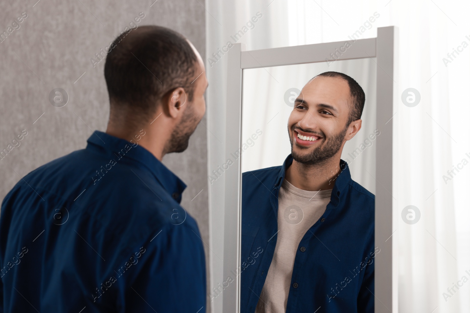 Photo of Smiling man looking at mirror at home