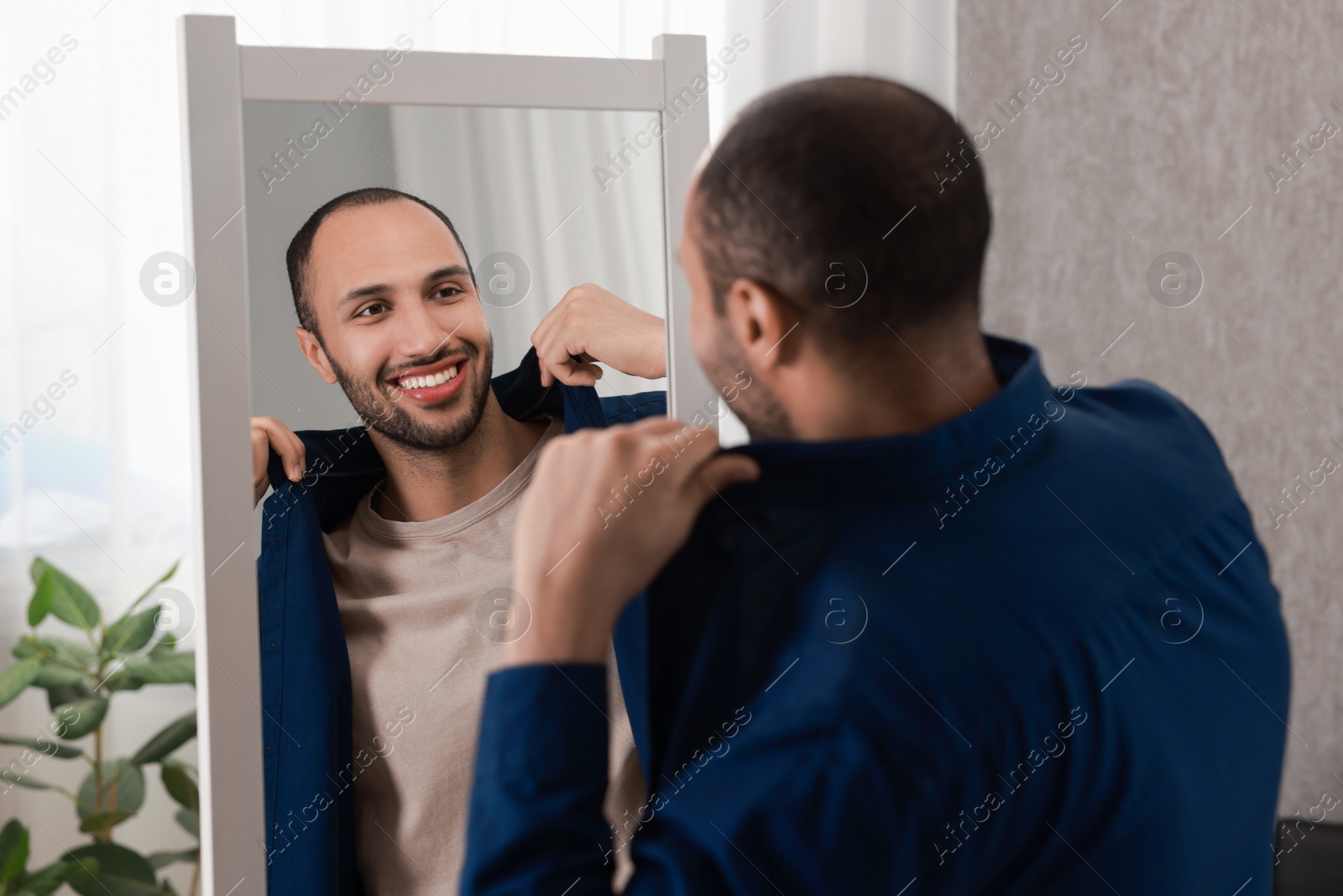 Photo of Smiling man looking at mirror at home