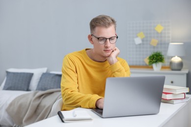 Photo of Student preparing for exam with laptop at table indoors