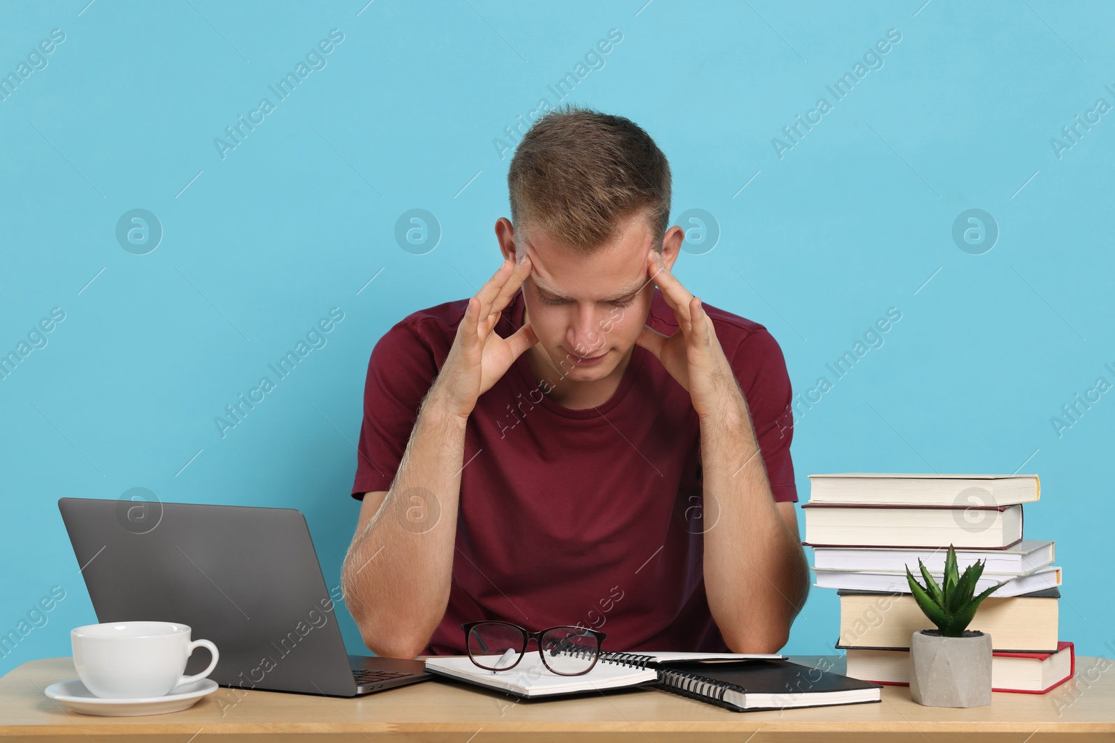 Photo of Student preparing for exam at table against light blue background