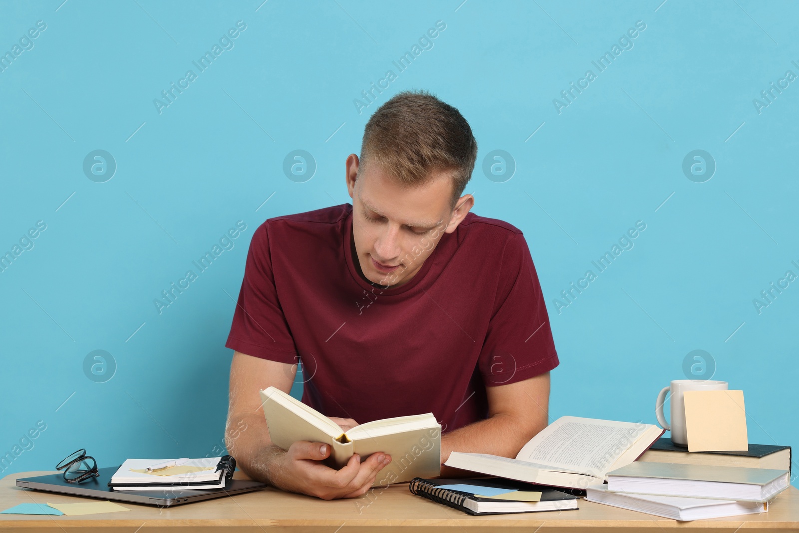 Photo of Student preparing for exam at table against light blue background