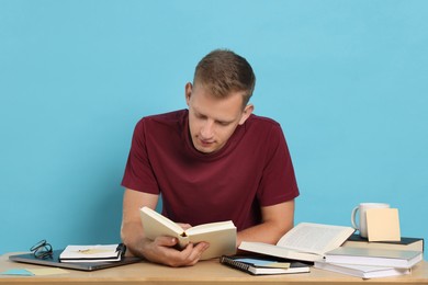 Photo of Student preparing for exam at table against light blue background