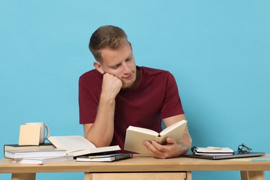 Photo of Student preparing for exam at table against light blue background