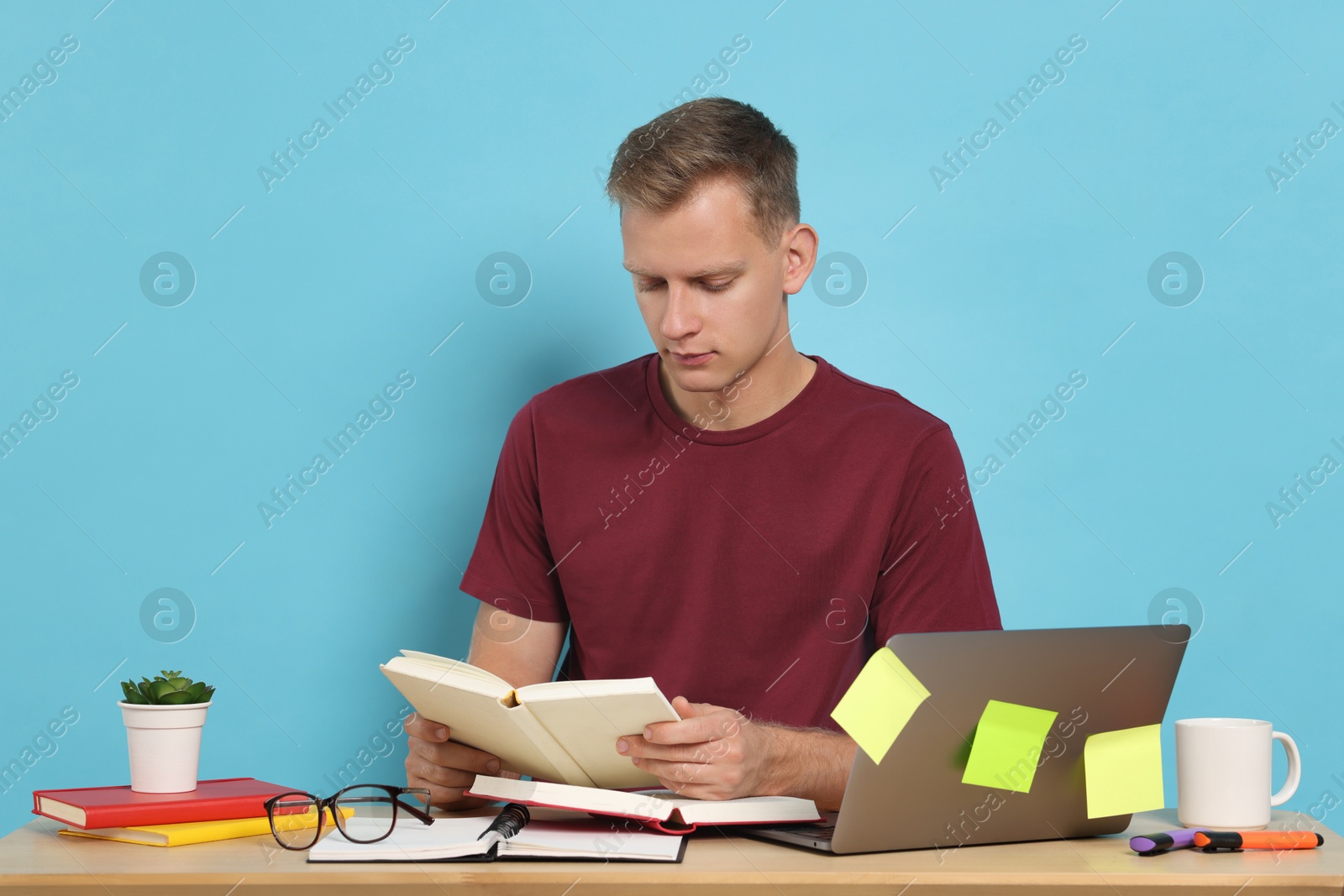 Photo of Student preparing for exam at table against light blue background