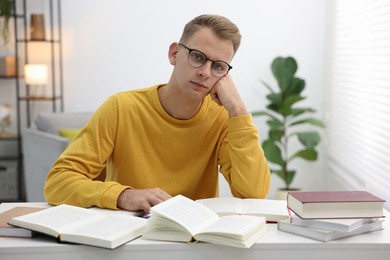 Photo of Preparing for exam. Student with books at table indoors