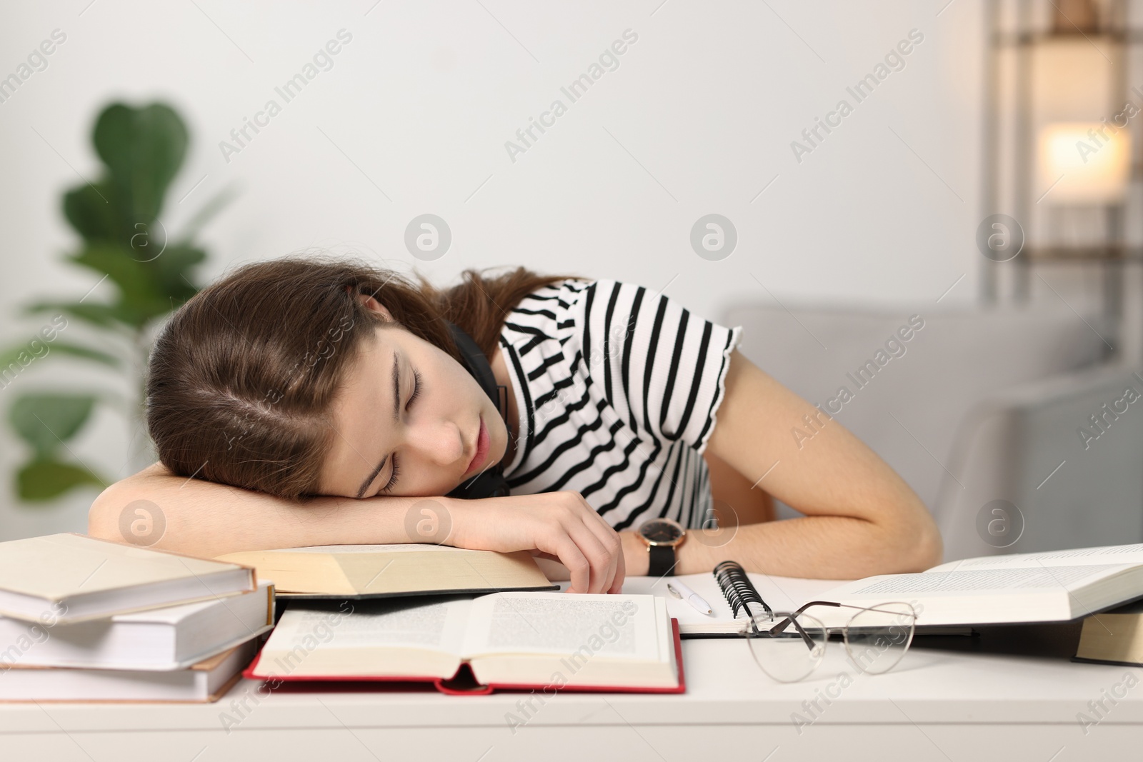 Photo of Preparing for exam. Tired student sleeping among books at table indoors