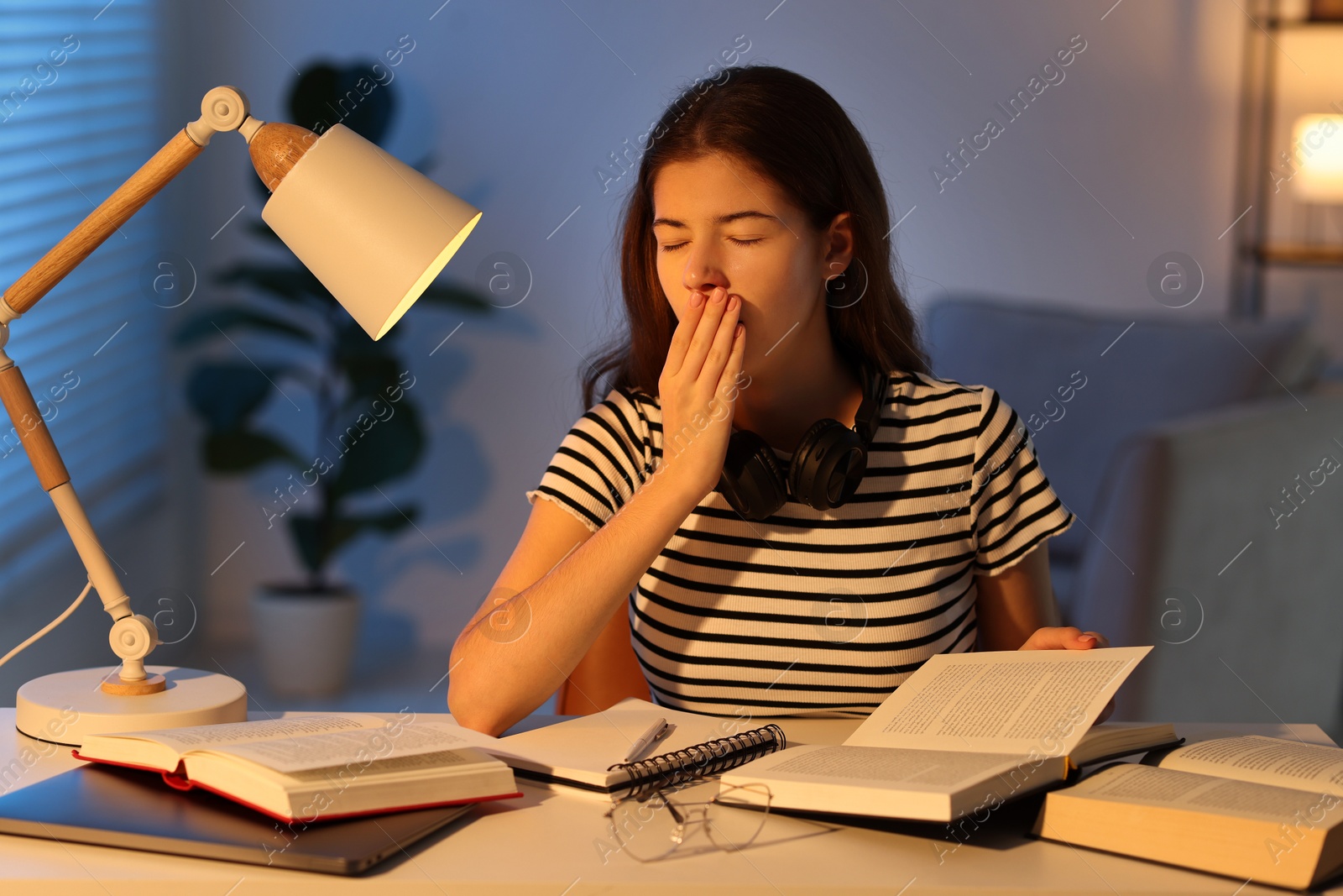 Photo of Preparing for exam. Tired student with books at table indoors