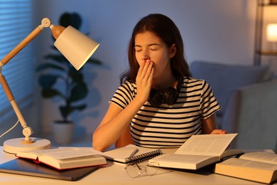 Photo of Preparing for exam. Tired student with books at table indoors