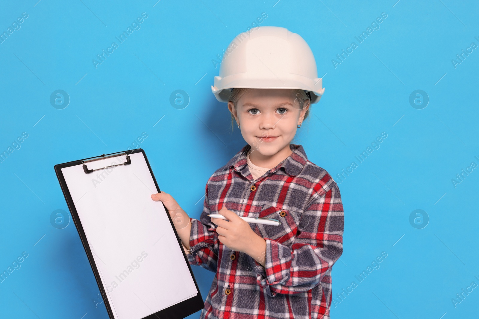 Photo of Little girl with clipboard pretending to be architect on light blue background. Dreaming of future profession