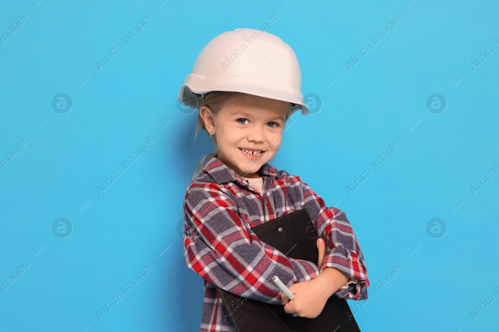 Photo of Little girl with clipboard pretending to be architect on light blue background. Dreaming of future profession