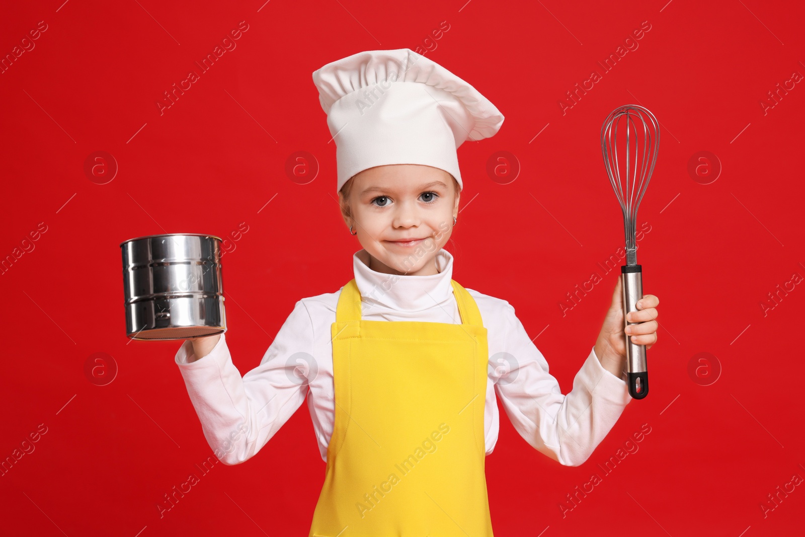 Photo of Little girl with utensils pretending to be chef on red background. Dreaming of future profession