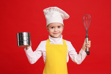 Photo of Little girl with utensils pretending to be chef on red background. Dreaming of future profession