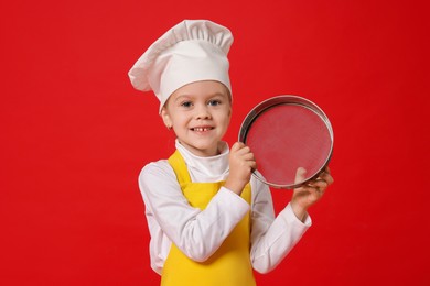 Photo of Little girl with sieve pretending to be chef on red background. Dreaming of future profession