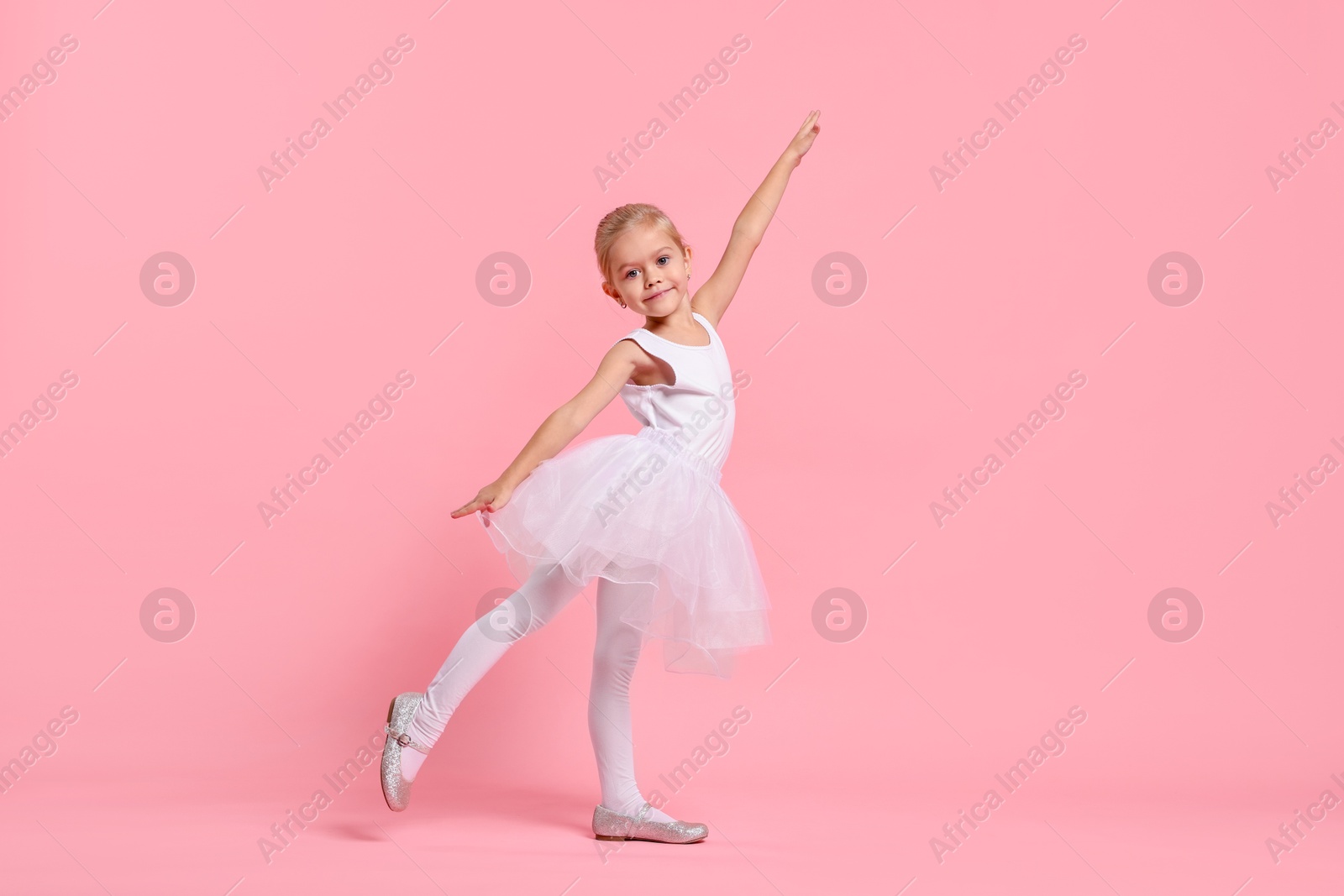 Photo of Little girl pretending to be ballerina on pink background. Dreaming of future profession