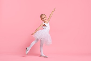 Photo of Little girl pretending to be ballerina on pink background. Dreaming of future profession