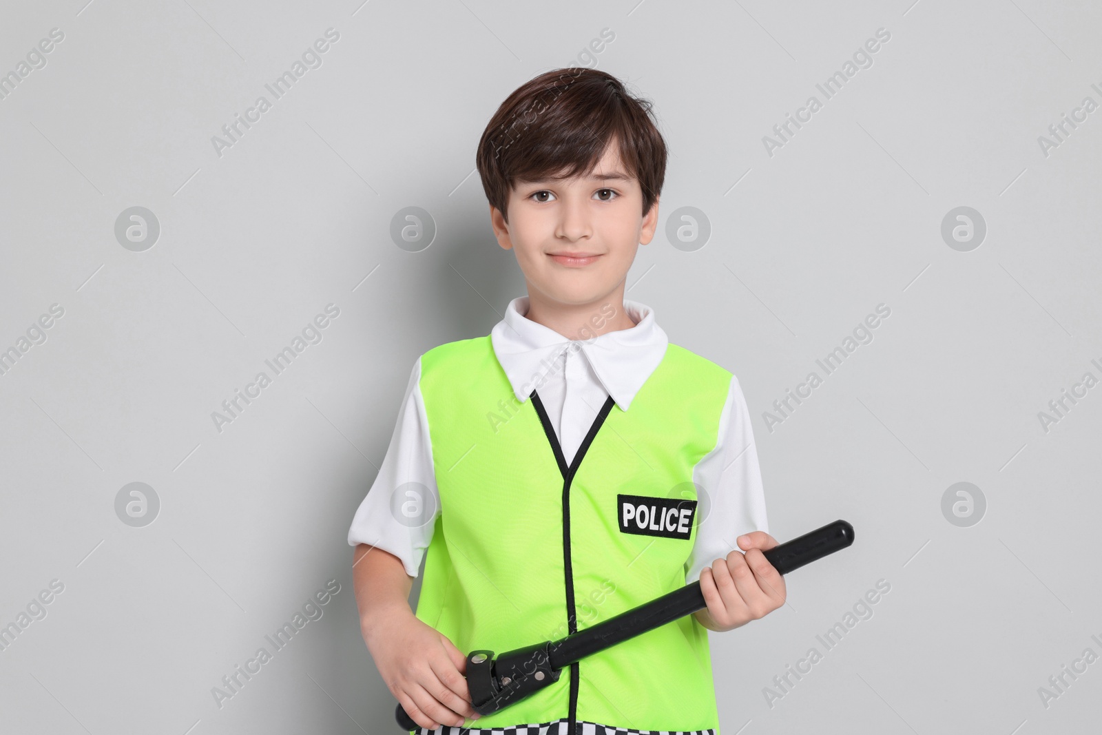 Photo of Boy pretending to be policeman on light grey background. Dreaming of future profession