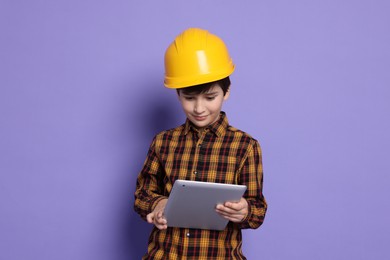 Photo of Boy with tablet pretending to be architect on violet background. Dreaming of future profession