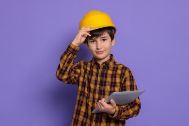 Boy with tablet pretending to be architect on violet background. Dreaming of future profession