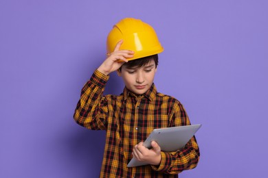 Photo of Boy with tablet pretending to be architect on violet background. Dreaming of future profession