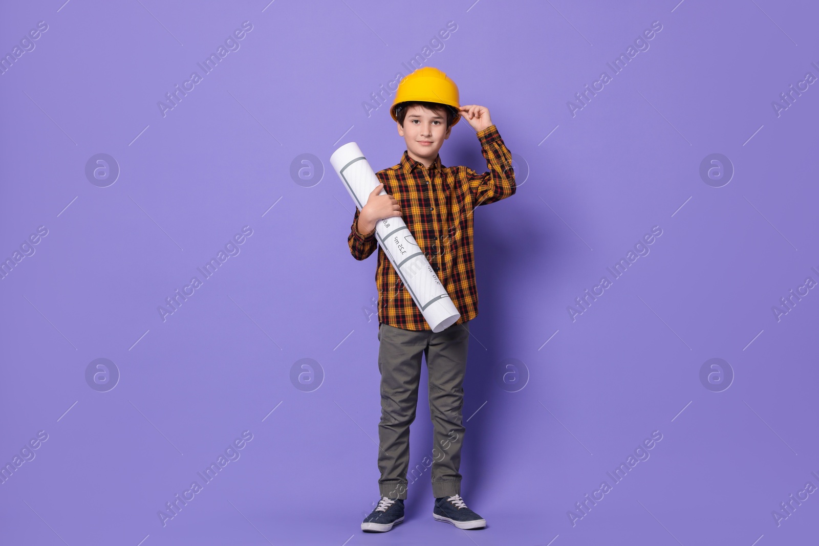 Photo of Boy with house plan pretending to be architect on violet background. Dreaming of future profession