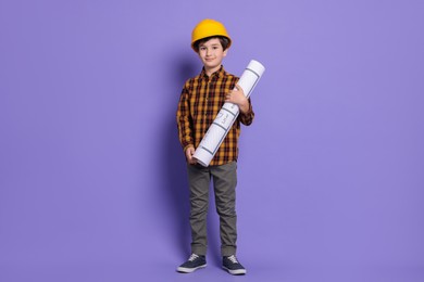 Photo of Boy with house plan pretending to be architect on violet background. Dreaming of future profession