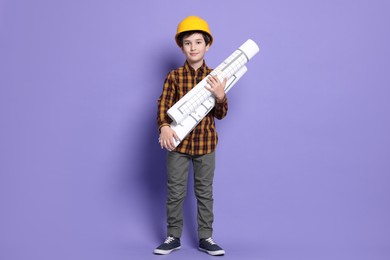 Photo of Boy with house plan pretending to be architect on violet background. Dreaming of future profession