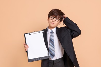 Photo of Boy with clipboard pretending to be accountant on beige background. Dreaming of future profession