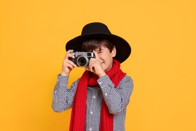 Photo of Boy with camera pretending to be photographer on orange background. Dreaming of future profession