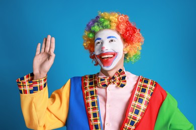 Photo of Portrait of happy clown waving on blue background