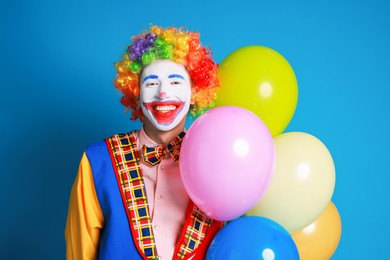 Photo of Happy clown with colorful balloons on blue background