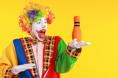 Photo of Emotional clown with juggling club on yellow background