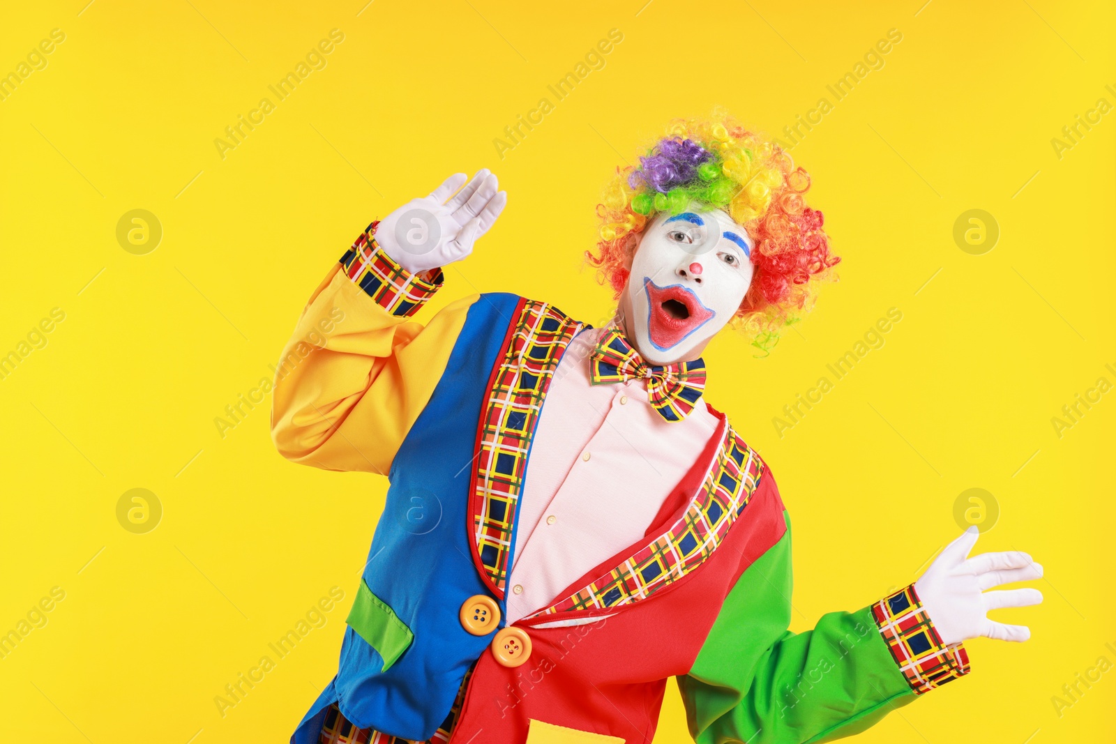 Photo of Portrait of emotional clown on yellow background