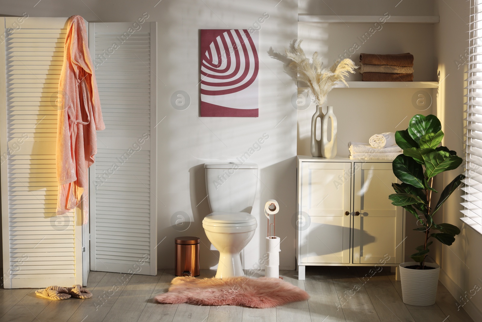 Photo of Ceramic toilet bowl, folding screen and necessities in restroom