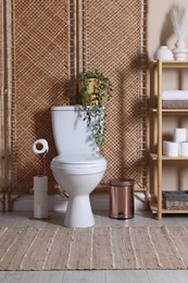 Photo of Ceramic toilet bowl, folding screen and necessities in restroom